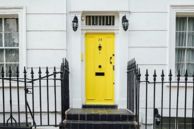 Steps leading up to a white facade house with a yellow front door